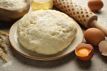 Fresh dough, ingredients and rolling pin on grey table, closeup