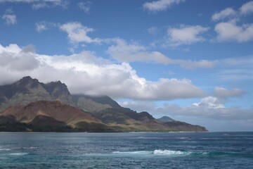 Naklejka premium Clouds hovering over the lush mountains of a tropical island