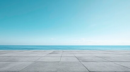 Empty concrete platform overlooking a calm ocean under a clear blue sky.
