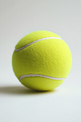 A single yellow tennis ball with white lines on a white background surface
