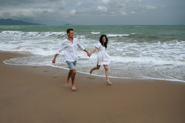 beautiful young couple in love runs along the beach by the sea in summer on vacation
