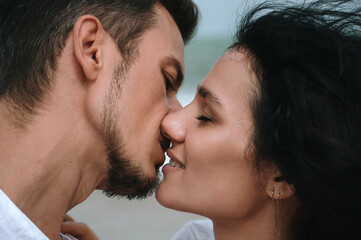 Fototapeta premium couple in love kissing on the beach by the sea in summer close-up