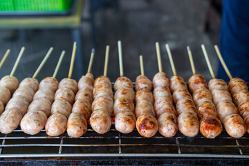 northeastern sausage on stick or skewered and arranged grilled burn on charcoal stove or isan sausage and barbecue meatball for traditional thai street food in local thailand or esan sausages