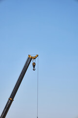 Fototapeta premium crane boom, machine used to move materials system of a boom, hoist, wire ropes or chains, and sheaves for lifting and relocating heavy objects, construction site, blue sky