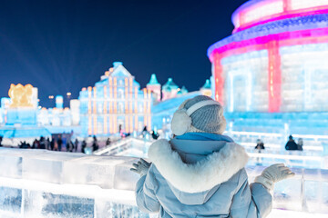 Young happy female tourist enjoying at ice and snow world festival at night in Harbin, China