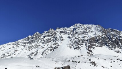 A breathtaking view of a majestic snow-covered mountain range under a deep, clear blue sky. 