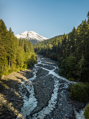 A serene scene featuring a snow-covered mountain, lush coniferous forest, and a winding river flowing through a picturesque valley under a clear blue sky, washington state. (version 2)