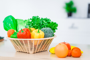 A nutritionist's table neatly arranged with a basket overflowing with fresh vegetables and fruits, including lettuce, kale, bell peppers, bananas, onions, and tomatoes, health and nutrition.