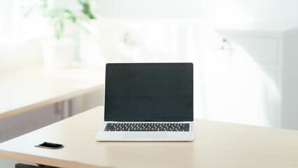 Blank white laptop on blank office desk with blurry white background for display your ads.