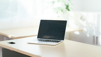 Fototapeta premium Blank white laptop on blank office desk with blurry white background for display your ads.