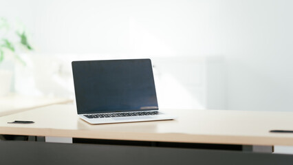 Fototapeta premium Blank white laptop on blank office desk with blurry white background for display your ads.