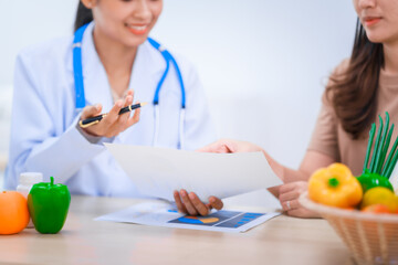 Obraz premium Female Asian nutritionist providing consultations for weight loss. reduce belly fat, offering advice on nutrients, metabolism, hydration, balanced diets to improve overall health and wellness.