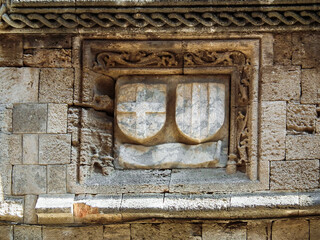 Partially  preserved coats of arms carved from the stone on building wall in historical part of Rhodes city on Rhodes island in Greece
