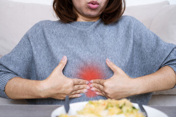 Asian woman suffering from epigastric burning and pain due to dyspepsia and acid reflux, feeling...