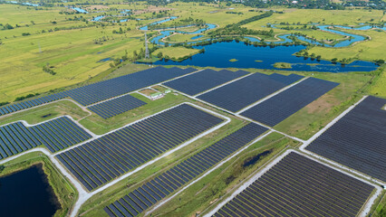 Drone shot aerial view solar energy array provides renewable power in large scale facility surrounded by greenery and water in rural place. Solar farm at the countryside