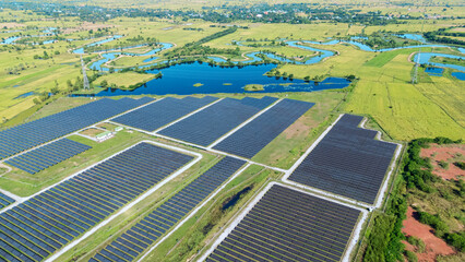Drone shot aerial view solar energy array provides renewable power in large scale facility surrounded by greenery and water in rural place. Solar farm at the countryside