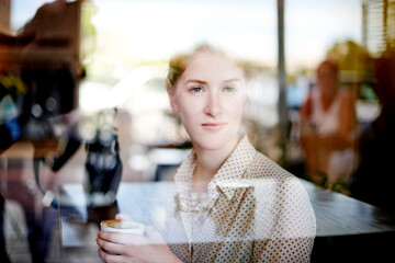 Thinking, window and woman with coffee, cafe and relax with drink in morning, reflection and consumer. Glass, customer and person with tea for breakfast, enjoying and warm beverage for break in shop