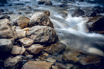Large rocks at the bottom of a stormy river.
