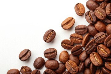 Aromatic roasted coffee beans scattered on a surface, their rich brown color and enticing aroma filling the frame.
