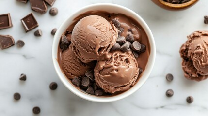 Two scoops of rich, decadent chocolate ice cream, adorned with chocolate chips, in a pristine white bowl. A delectable treat captured from an overhead perspective.