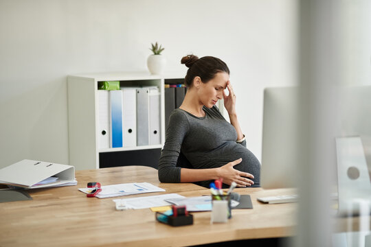 Business, pregnant woman and maternity headache in office with discomfort, burnout and mental health. Pregnancy, professional and stress with migraine, uncomfortable ache and overworked at workplace