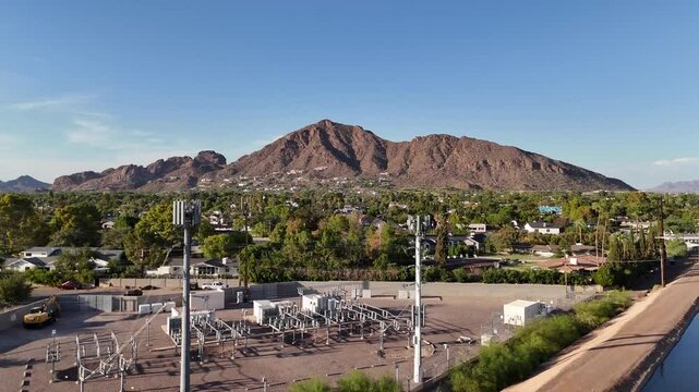 Drone Ascending over canal Showing Camelback Mountain with houses, trees, and cellphone towers