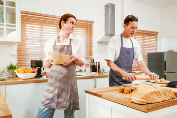 Loving gay couple enjoys baking together in their modern kitchen, sharing laughter and teamwork in aprons, prepare fresh bread and pastries, highlighting LGBTQ+ love, domestic life, and joyful moments