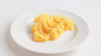 Mashed potatoes in a plate on a white table. Potato dishes. The menu in the children's dining room. Side dish for cutlets, gravies.
