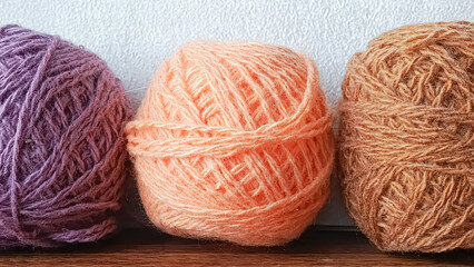 Three balls of threads stand on a wooden table in a row. Wool yarn. Manufacture of knitted toys.