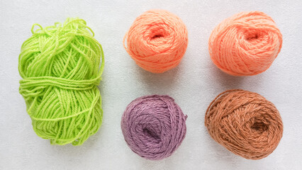 A large, green skein of knitting thread and four colored balls of yarn on the table. Types of yarn for knitting toys. 