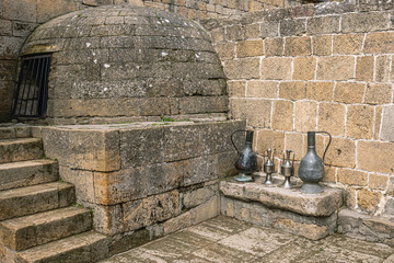 Antique metal vessels for water and wine. Copper jugs in an ancient city near a stone wall. Antique...