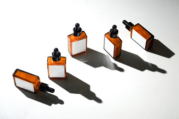 Five amber bottles with droppers are neatly positioned on a light surface, creating a visually appealing arrangement with soft shadows