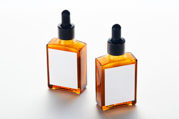 Two elegant amber glass bottles with droppers sit neatly on a pristine white surface, suitable for...