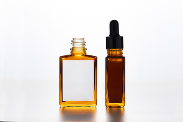 Two stylish amber bottles, one square and one tall with a dropper, showcase a clear liquid against a white backdrop, emphasizing simplicity