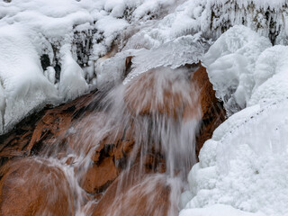 winter photography with ice, water and sandstone rocks, ice icicles, running water