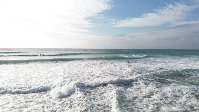 Surfers riding waves in sitges, spain on a sunny day