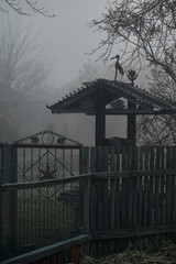 old well in the fog behind an old fence, autumn