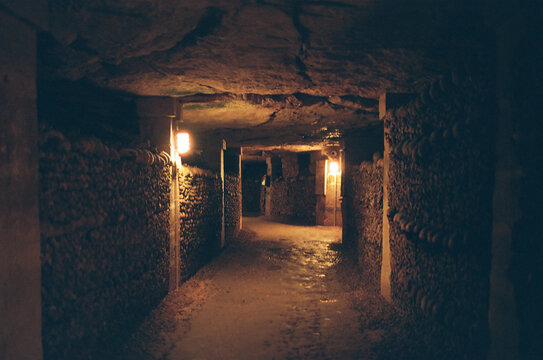 Dimly lit underground tunnel lined with human bones and skulls.