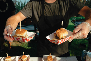 A food vendor serving fresh sliders in checkered paper trays