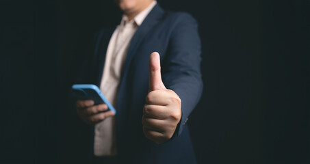 Professional man giving thumbs up with smartphone