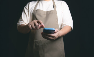 person in apron using smartphone in dark setting