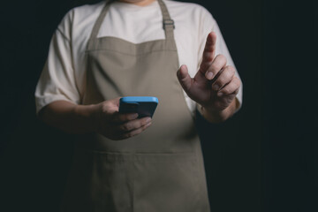 person in apron using smartphone, gesturing with one hand
