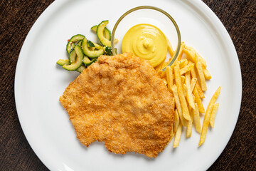 Enjoy a delectable plate featuring a golden-brown schnitzel accompanied by a creamy mustard dip,...