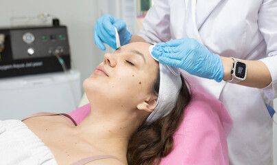 Naklejka premium woman is getting her face cleaned with a cloth. The woman is wearing a white headband and blue gloves