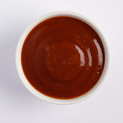A beautifully crafted sauce sits in a white bowl, showcasing its rich, dark red hue. The smooth texture invites culinary creativity, perfect for drizzling over tacos or enriching pasta dishes. 