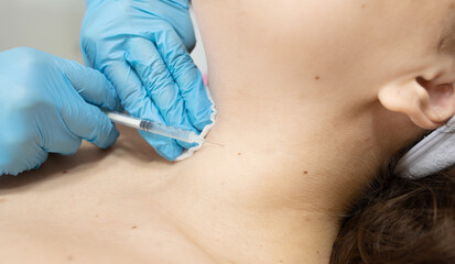  woman is getting injection in her neck. The woman is wearing blue gloves. The shot is being administered by a doctor © lashkhidzetim