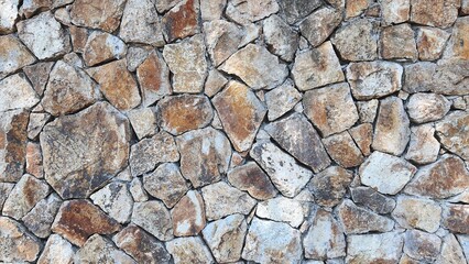 rock wall. Natural stone wall used as background or texture. Stone wall structure. Seaside stone wall texture background. Gray and brown stones mixed.