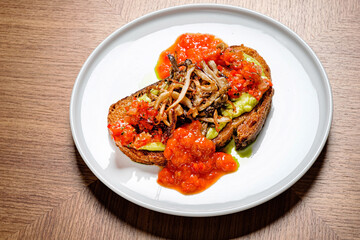 Delicious gourmet toast features a rich avocado spread topped with roasted mushrooms and a vibrant tomato sauce, perfect for a midday brunch. A feast for the eyes and palate.