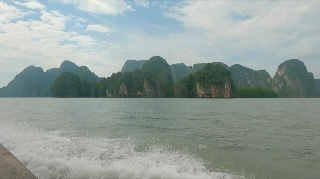 POV of speedboat along waterway in Phuket viewing rugged ancient rock formations