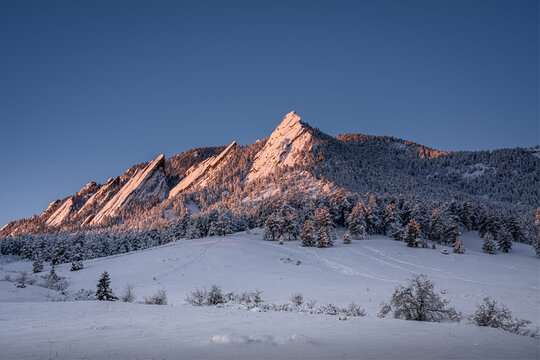 Sunrise glow on the Boulder flatirons after a snow storm